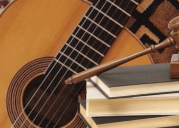Imagem de um violão e martelo jurídico em cima de livros