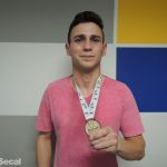 Imagem do aluno João Terluk, do curso de Jornalismo, segurando a medalha de primeiro lugar.