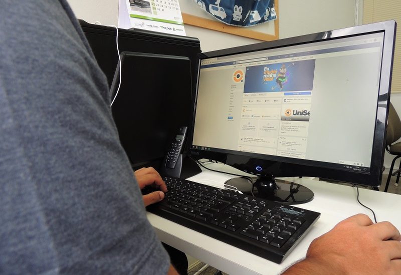 Imagem de uma pessoa mexendo em um computador. A página é do Facebook da UniSecal.