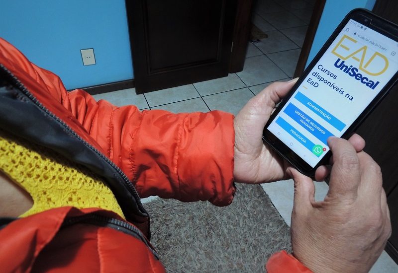 Foto de uma pessoa segurando um celular e acessando o site da EaD UniSecal